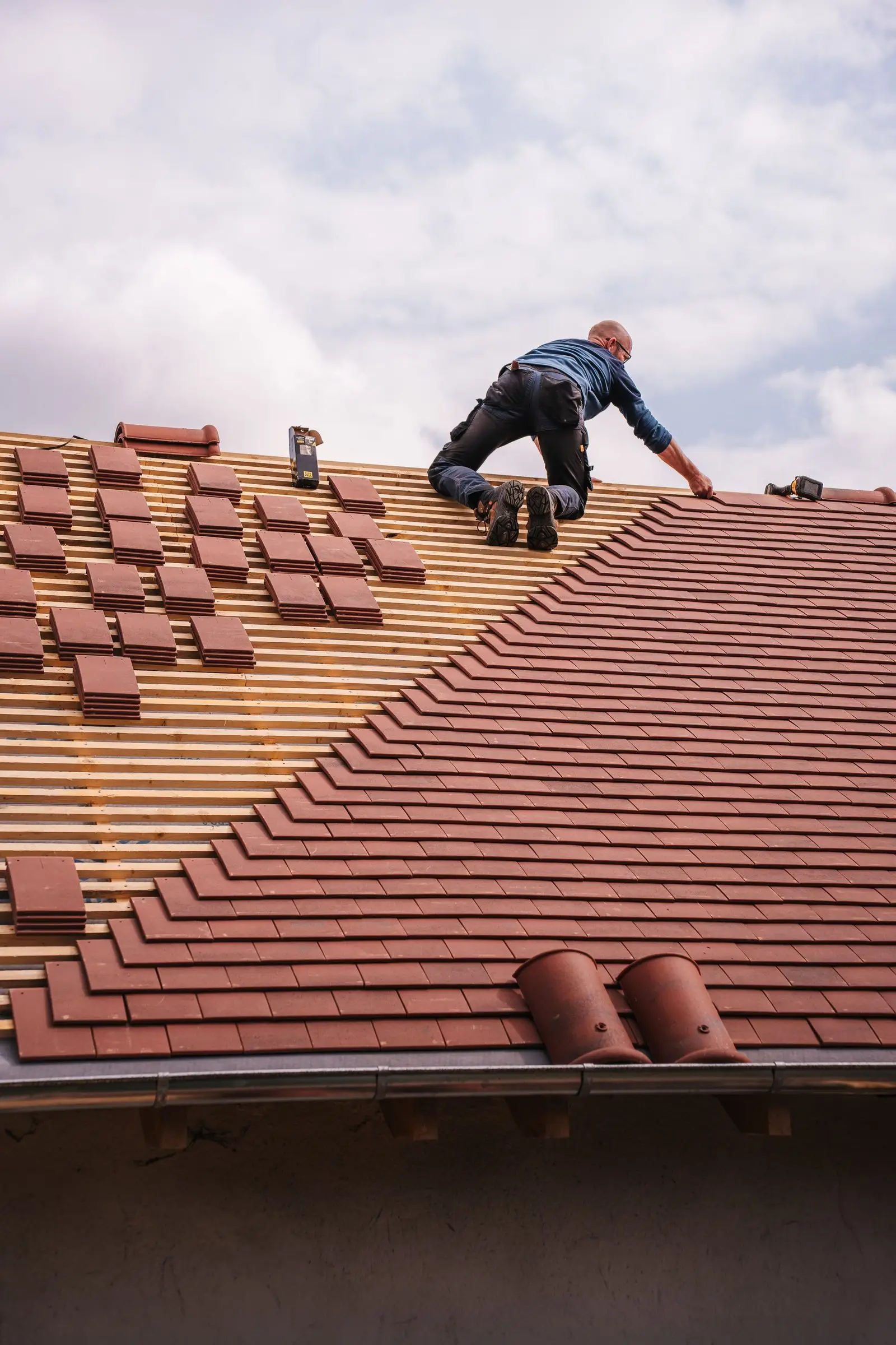 Roofer laying tiles on a sloped roof