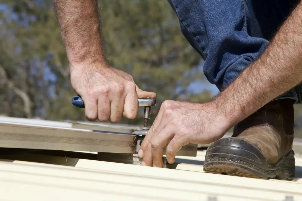 Hands fastening metal roof panels with a driver
