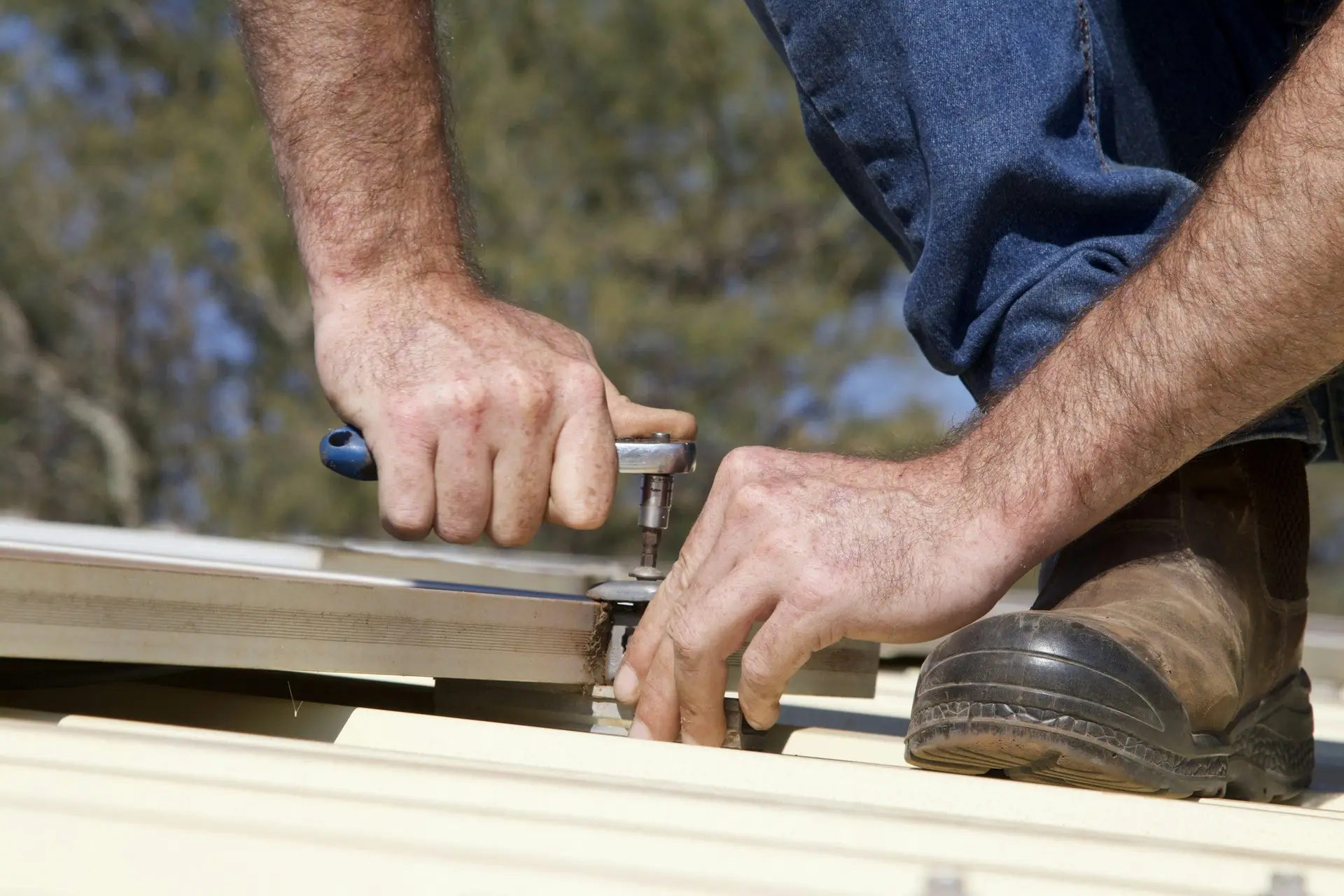 Hands fastening metal roof panels with a driver